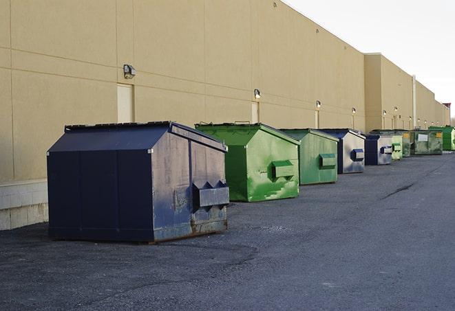 construction workers throw waste into a dumpster behind a building in Clifton Heights